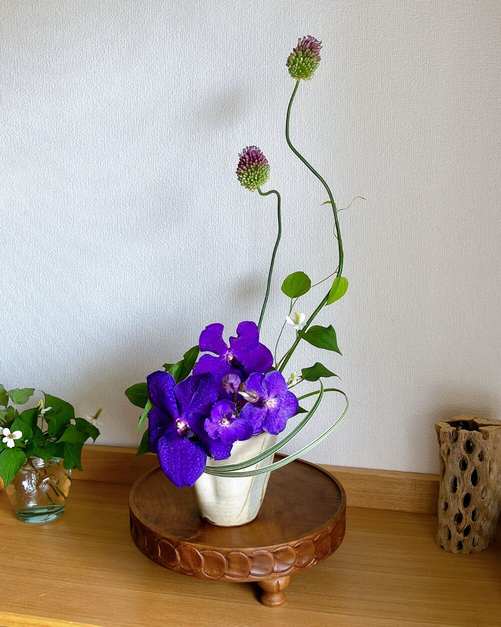 Close-up of a purple Vanda orchid and Allium styled with minimal greens in a Japanese ceramic vase.