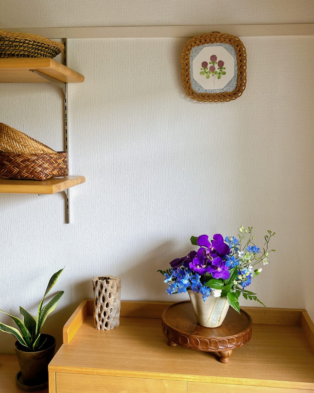 A minimalist arrangement of Vanda orchid and Delphinium placed against a wall with a blue floral tile.