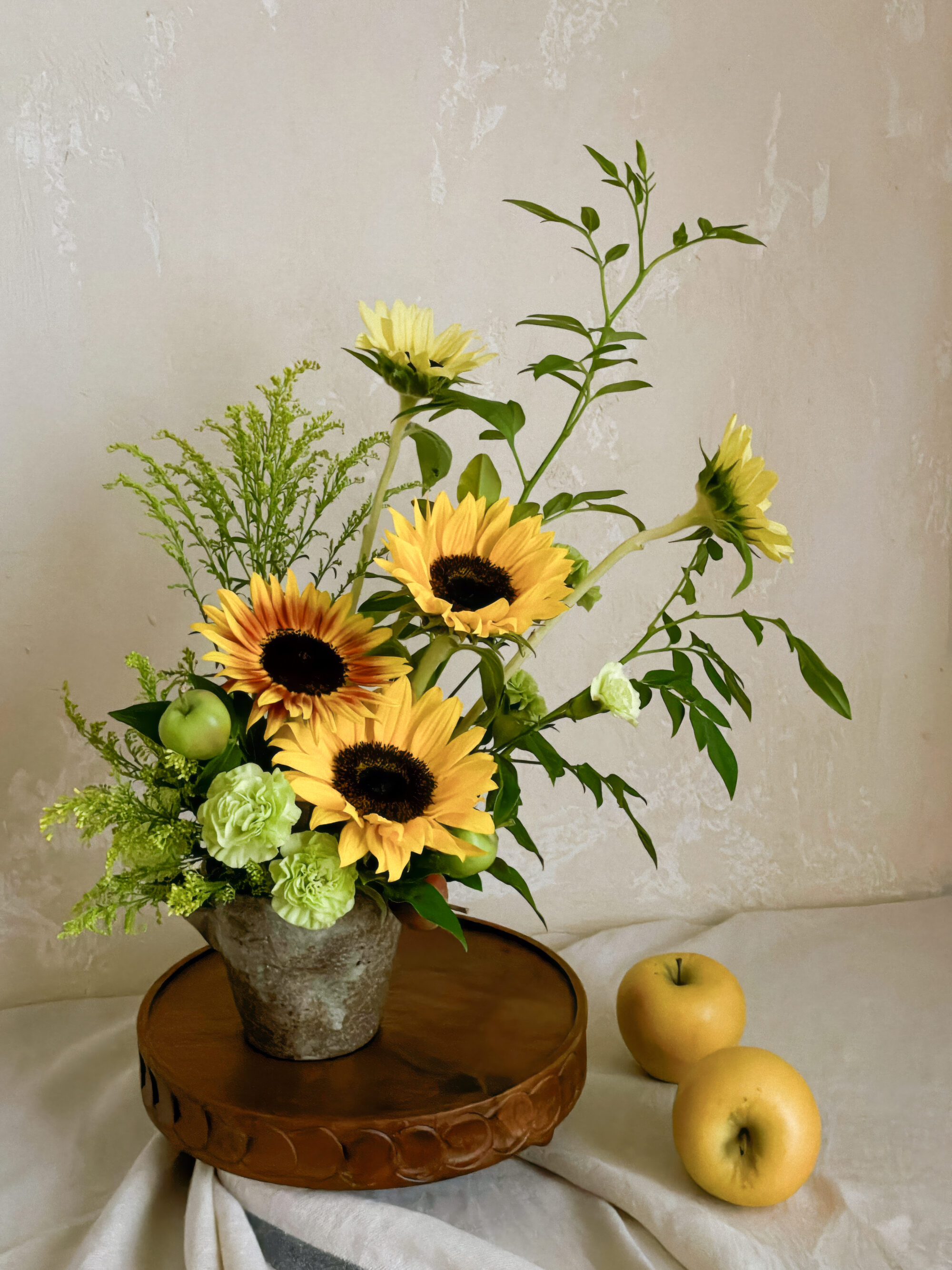 A fine-art photo preview of the flowing sunflower and green carnation arrangement isolated against a chic, dark moody backdrop.
