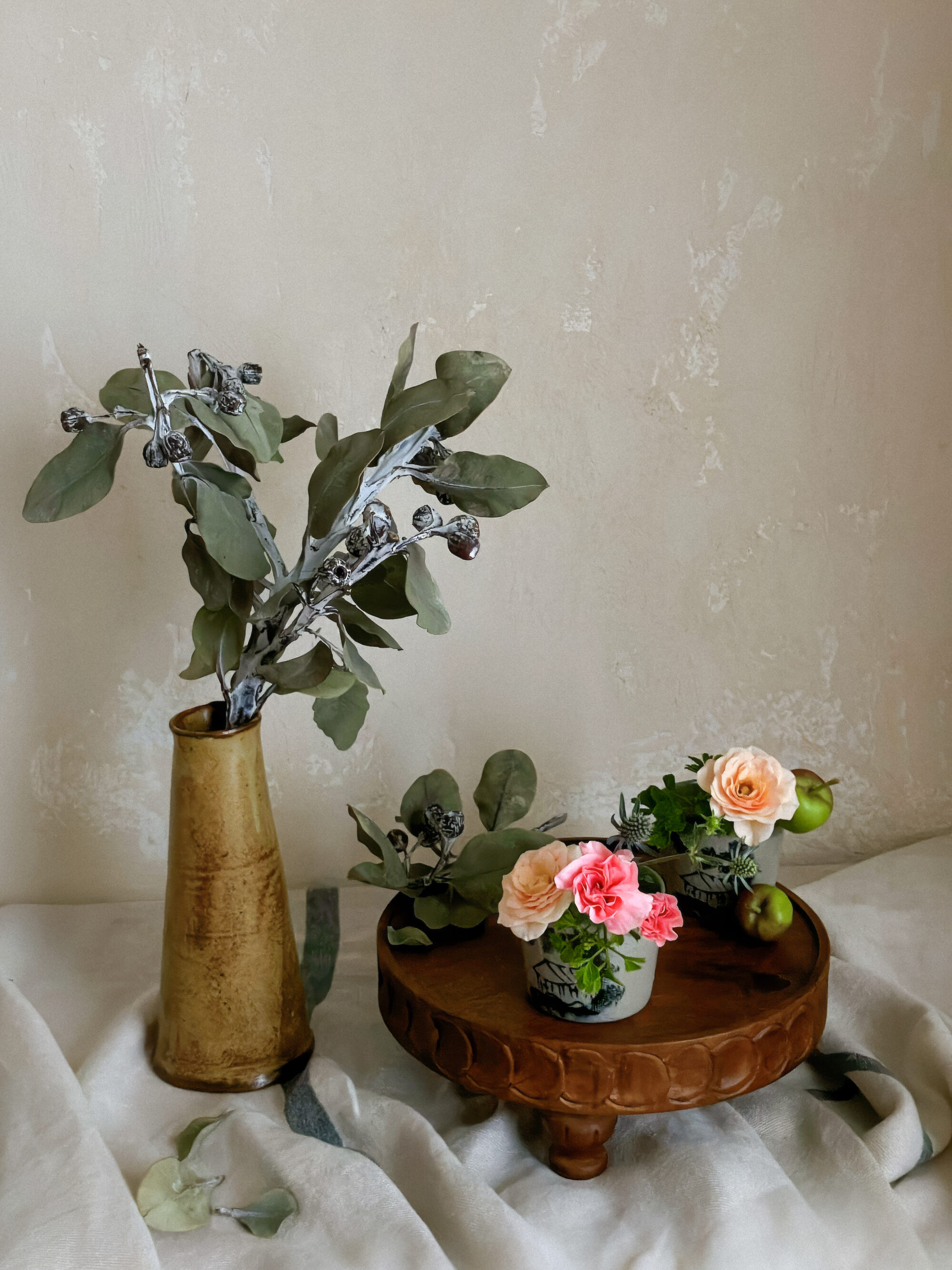 An art poster style still life photograph focusing on the rustic texture of dried tetragonanuts and soft petals in a Japanese soba choko cup.