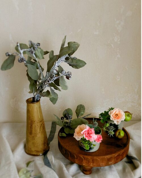 An art poster style still life photograph focusing on the rustic texture of dried tetragonanuts and soft petals in a Japanese soba choko cup.