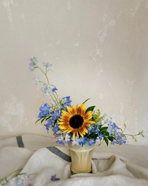 A fine-art photo preview of the single sunflower and blue flower styling, creating a striking contrast against a dark, chic backdrop.