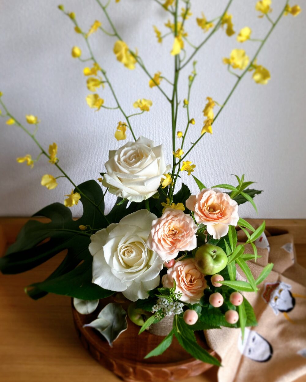 A close-up white rose and yellow oncidium orchids arrangement.