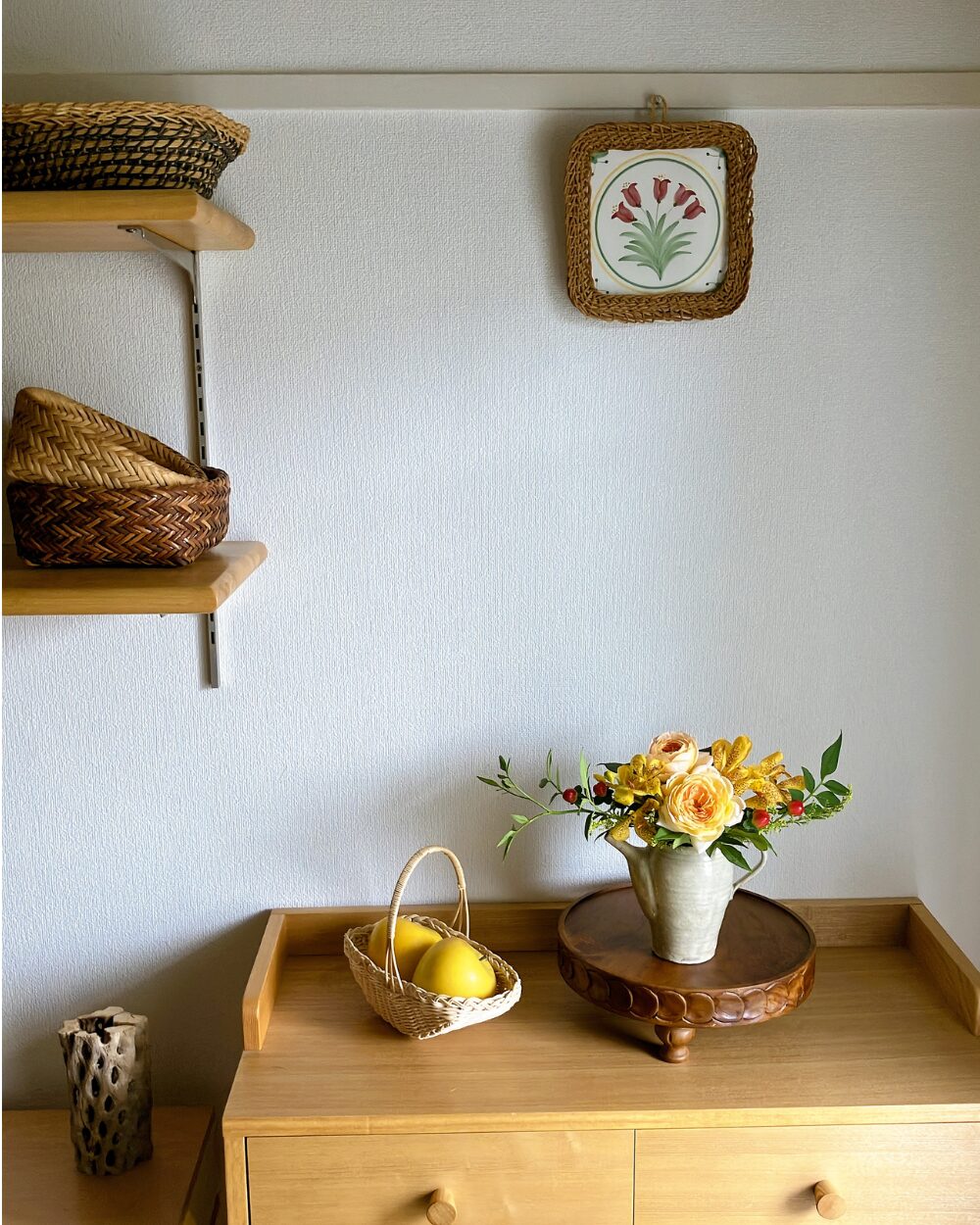 A long shot of the rose and orchid arrangement in a Japanese pottery pitcher styled on a shelf within the room.