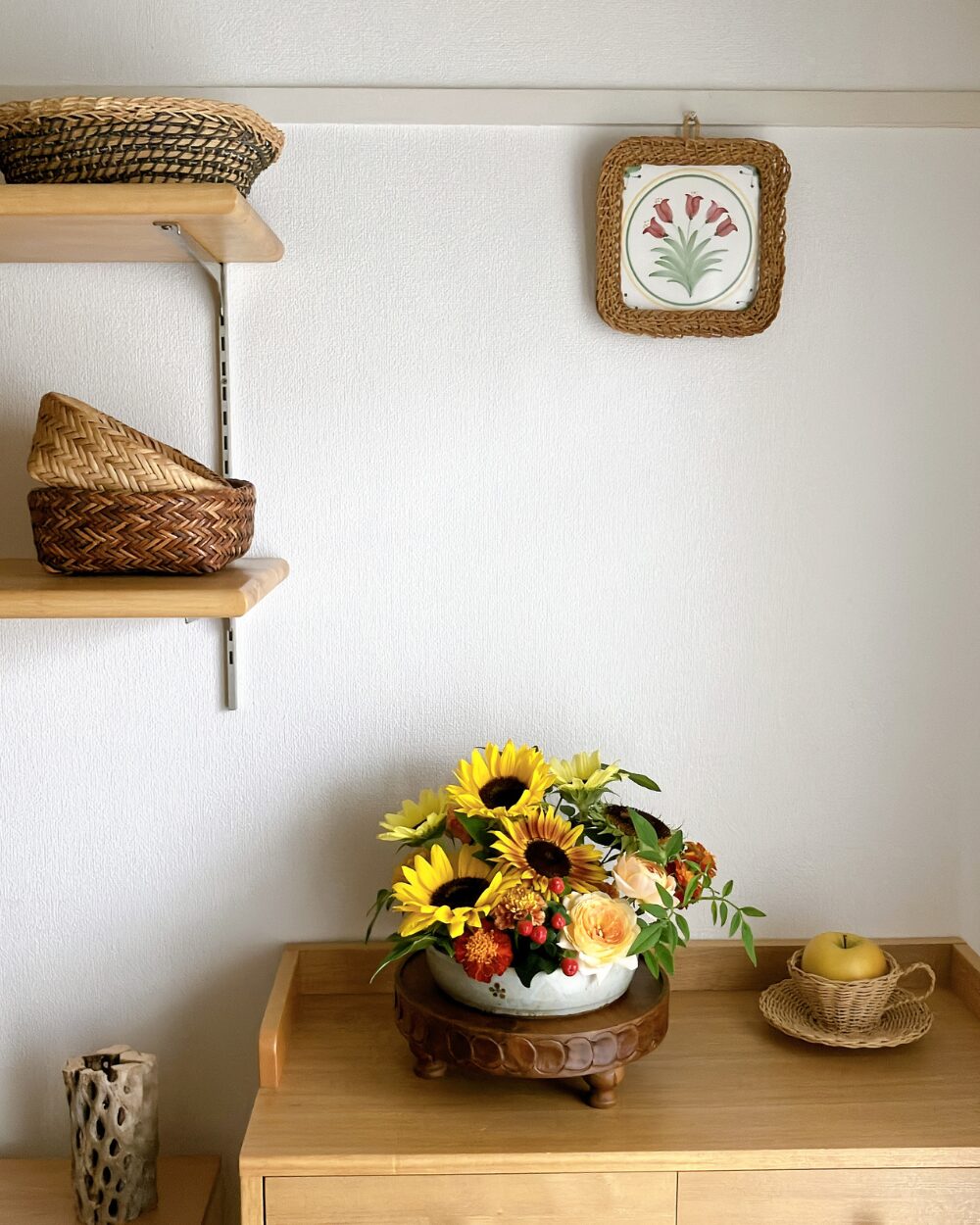 A wide view of a living room space featuring an abundant, low-styled flower dish with sunflowers and marigolds on a counter.