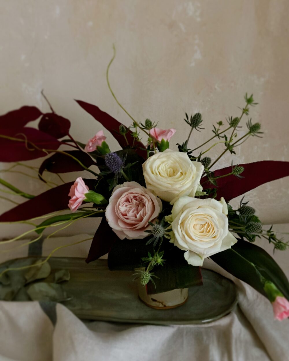 A detailed close-up showing the layers of white rose petals contrasted against the dark pink tone of preserved eucalyptus leaves.