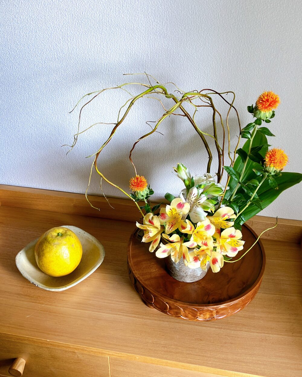 top-down view of alstroemeria and safflowers balanced in a ceramic bowl.