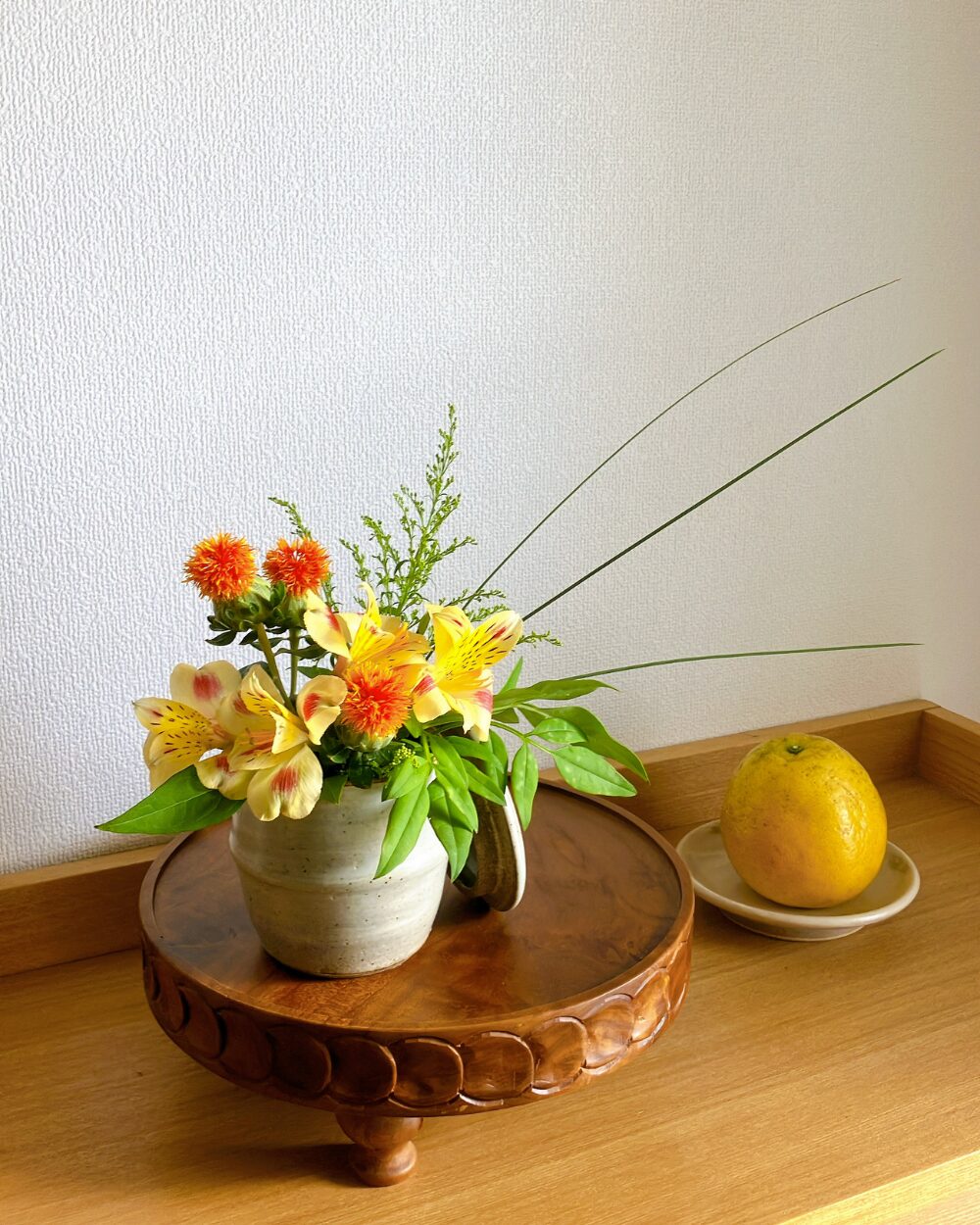 Alstroemeria in a small ceramic jar with its lid placed beside it.