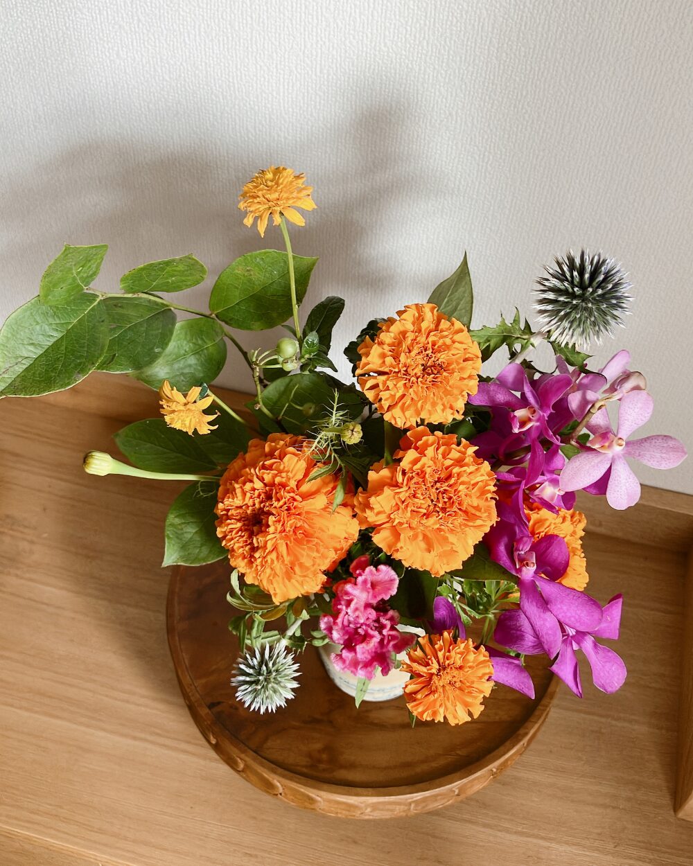 A top-down view of the floral arrangement featuring marigolds, mokara, and cockscomb in a Japanese ceramic vase.