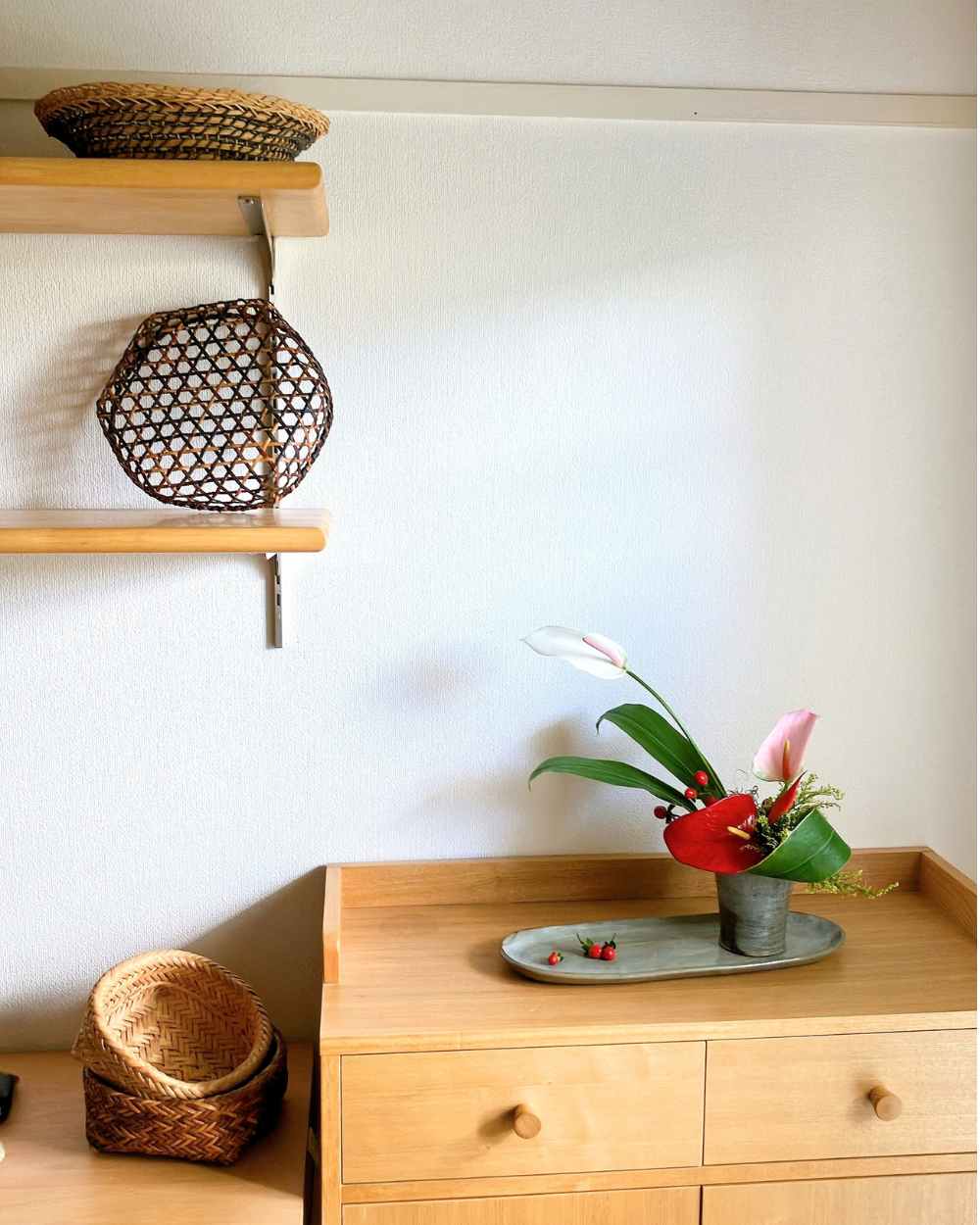 Minimalist Japanese ceramic flower arrangement featuring anthurium and red berries placed in a room