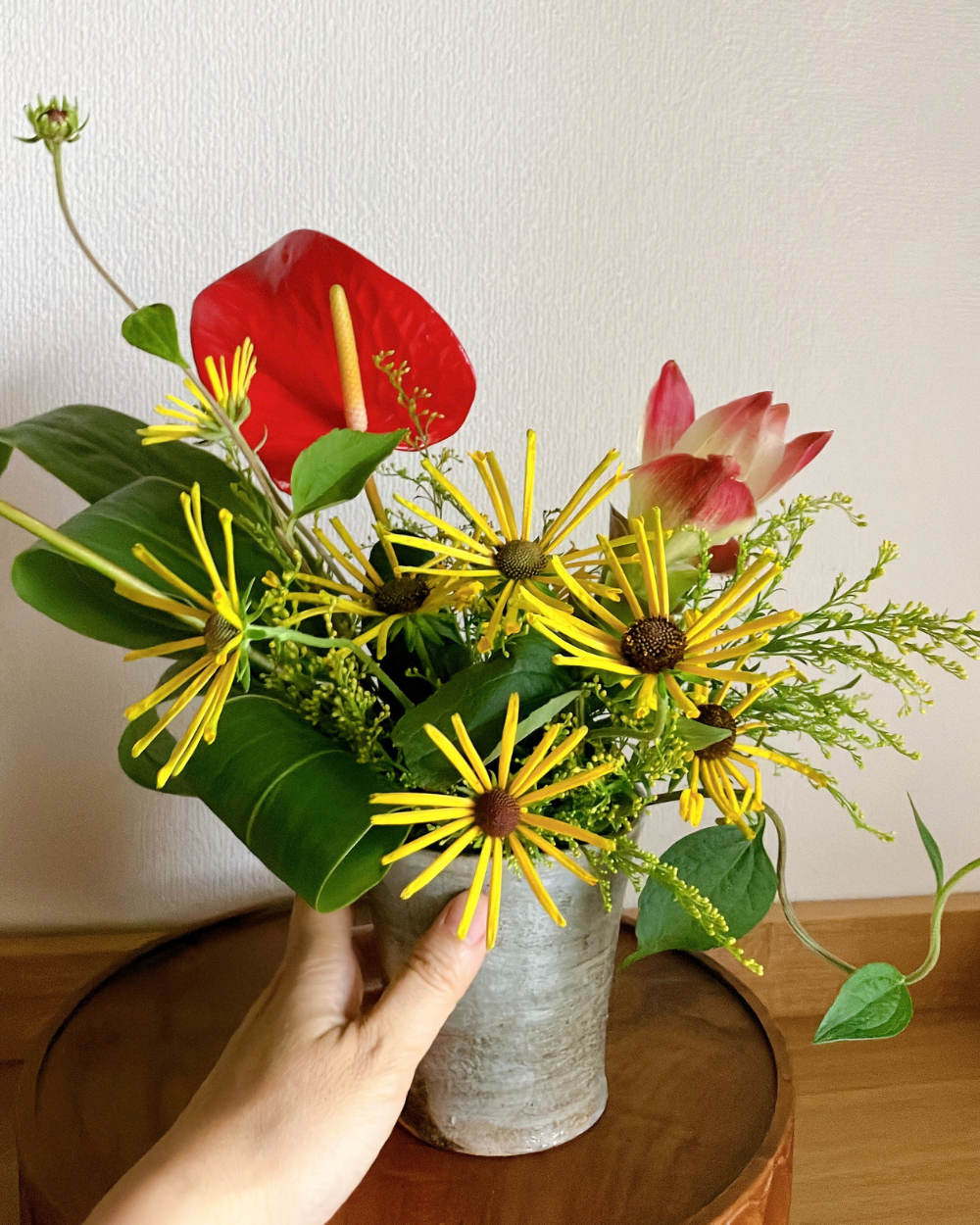 Closeup shot of a unique flower arrangement with yellow rudbeckia and anthurium